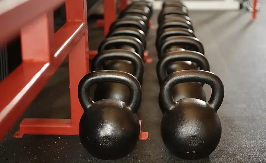 Osoby ćwiczące na zajęciach body pump z użyciem sprzętu fitness